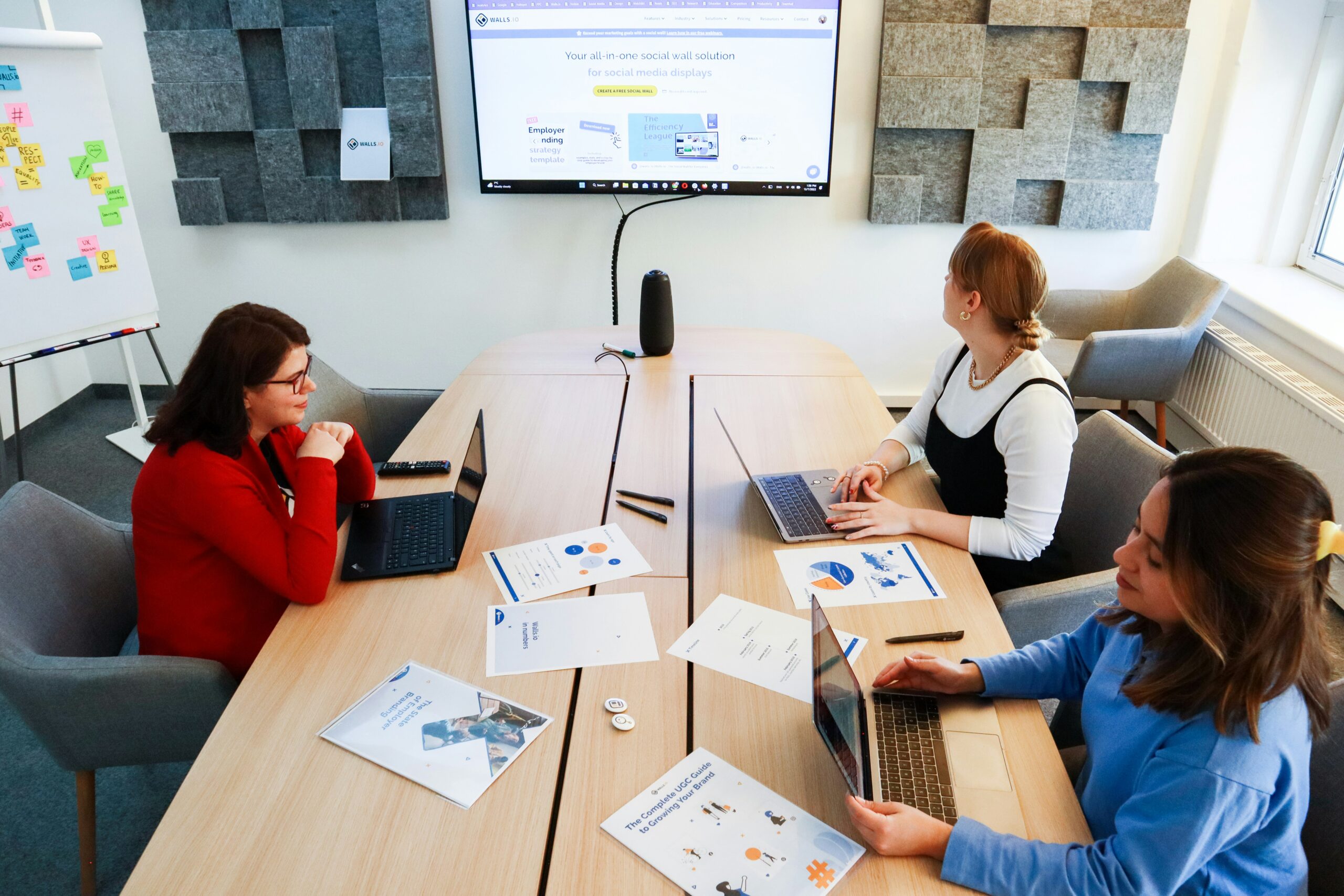 A trio of people at a table, focused on their laptops, collaborating on a project together.