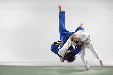 Two individuals executing a judo technique against a clean white backdrop, showcasing skill and athleticism.