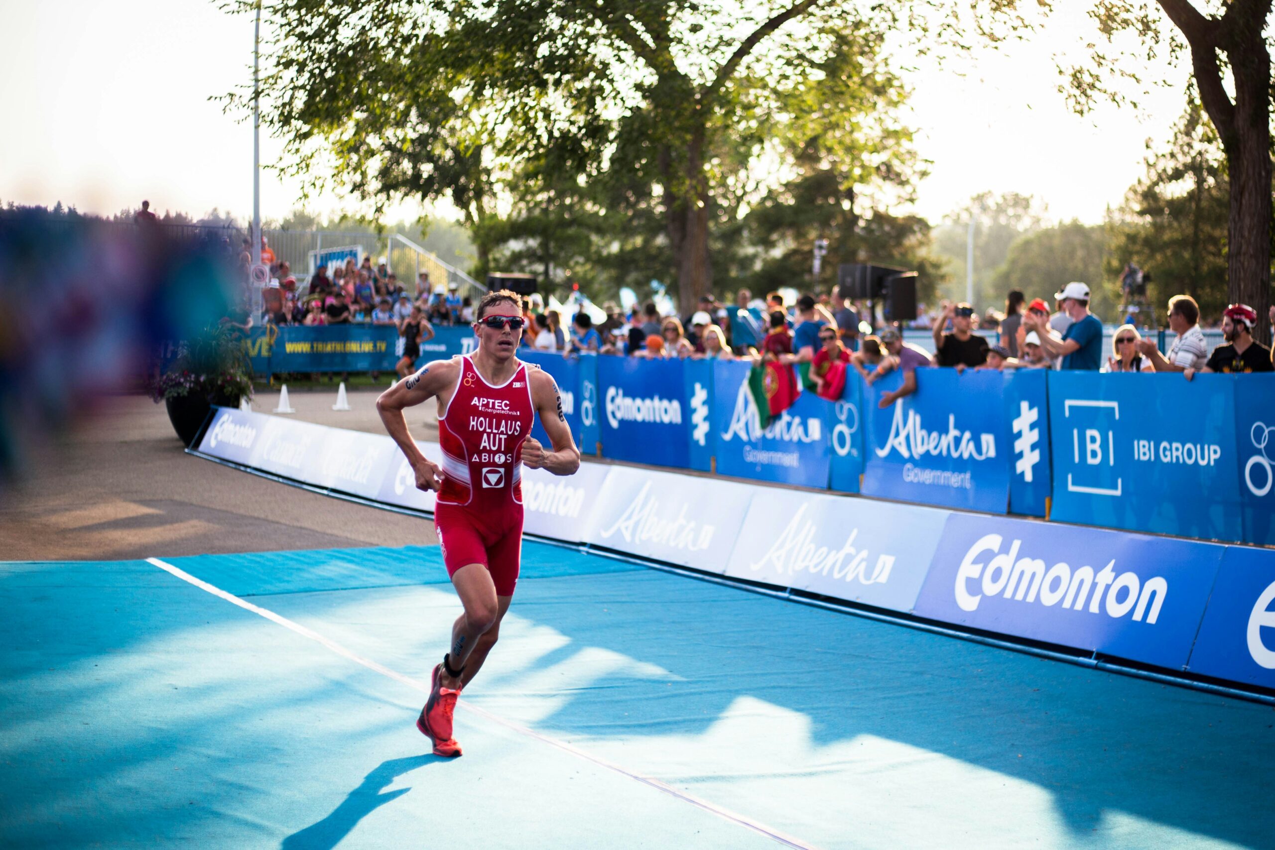 A man competing in a triathlon race, sprinting across a blue surface with determination and focus.